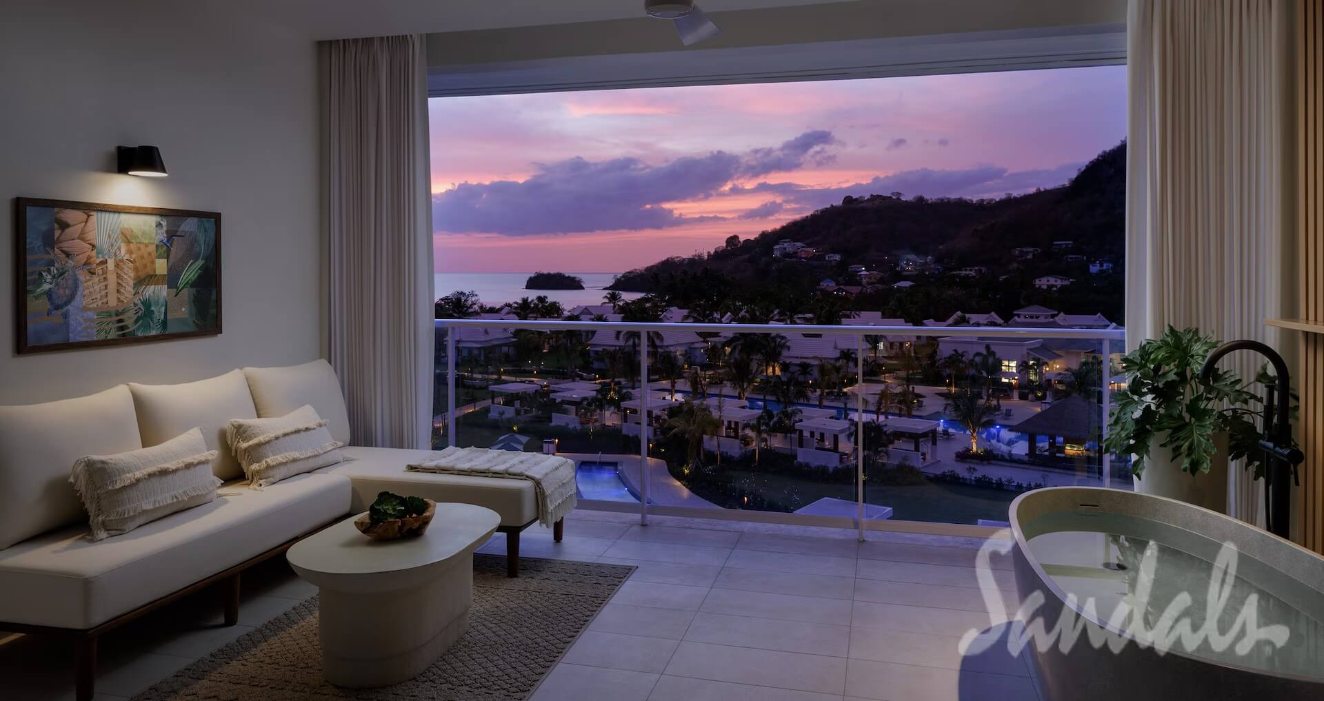 Sandals suite at sunset with a freestanding tub and a balcony overlooking the resort and sea